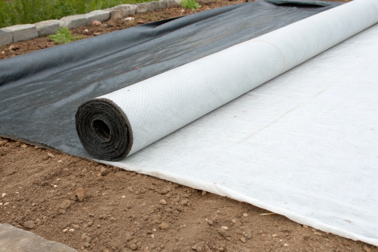 A side-by-side comparison of a thick, white nonwoven geotextile and a thin, black landscape fabric