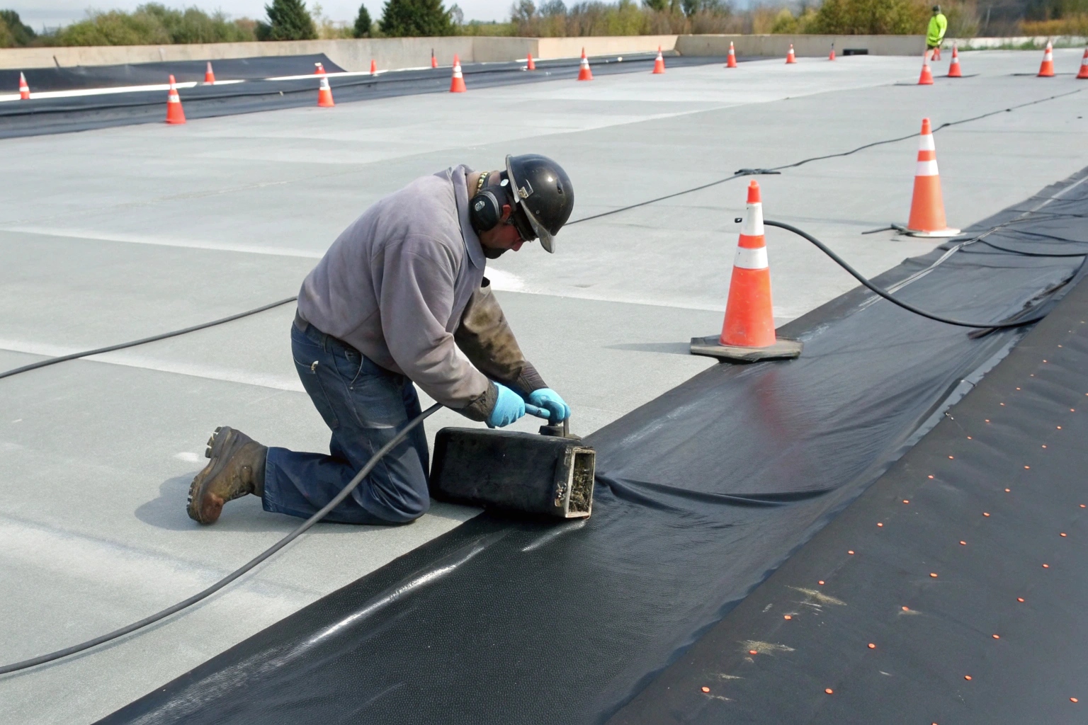 A technician cleaning a geomembrane seam with a wipe, with welding rods and a backing plate nearby