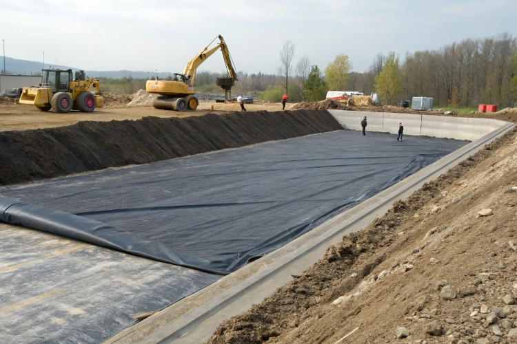 A section of geomembrane being covered with a protective layer of soil