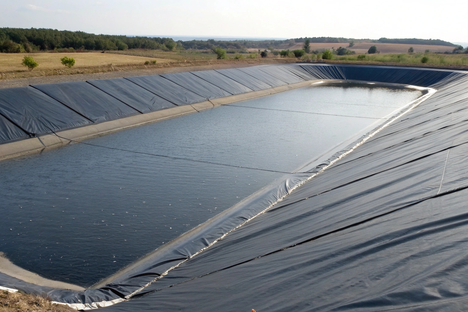 A technician performing thermal welding on a geomembrane seam in a reservoir