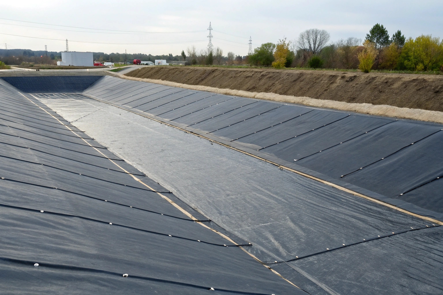 A cross-section diagram showing a geomembrane liner preventing water from seeping into the ground
