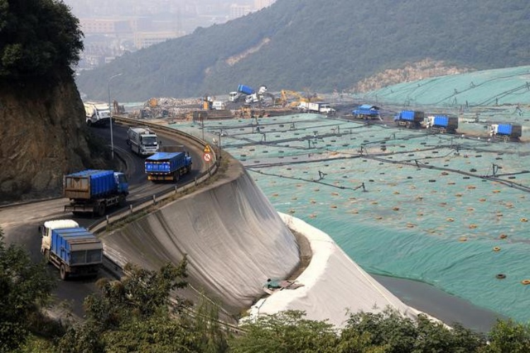 Low-ground-pressure dozer carefully spreading a layer of aggregate over an installed geotextile