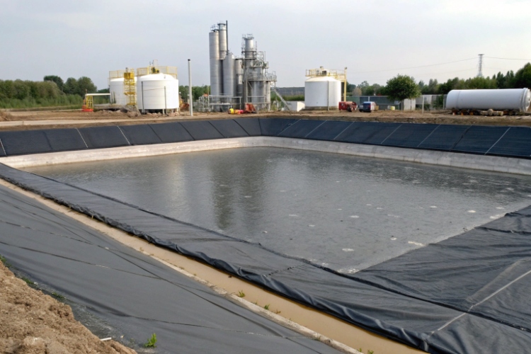 A large industrial wastewater pond lined with black HDPE geomembrane