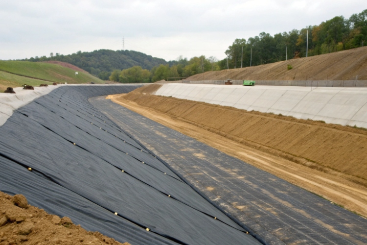 A photo of technicians performing a seam weld test on a textured geomembrane on a slope