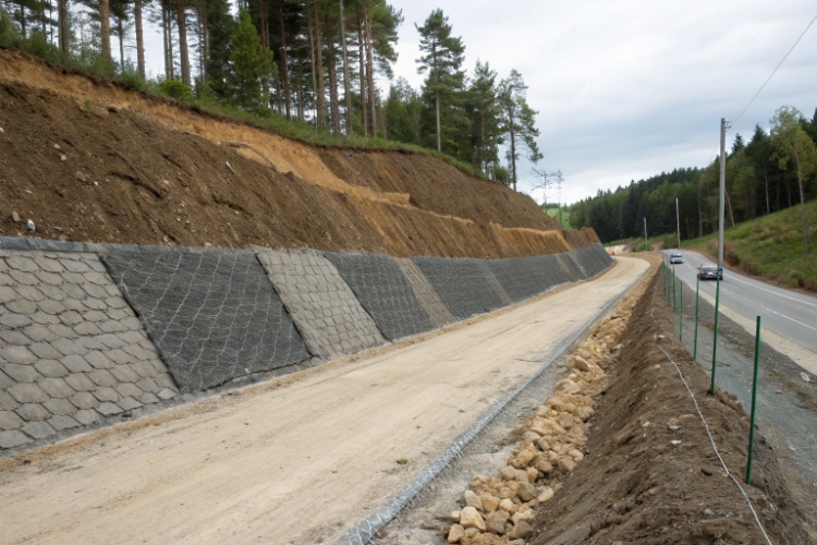 A cross-section illustration showing geotextile layers within a road base and an embankment to provide reinforcement