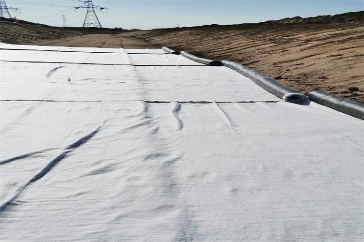 A roll of Geosynthetic Clay Liner (GCL) being unrolled during installation