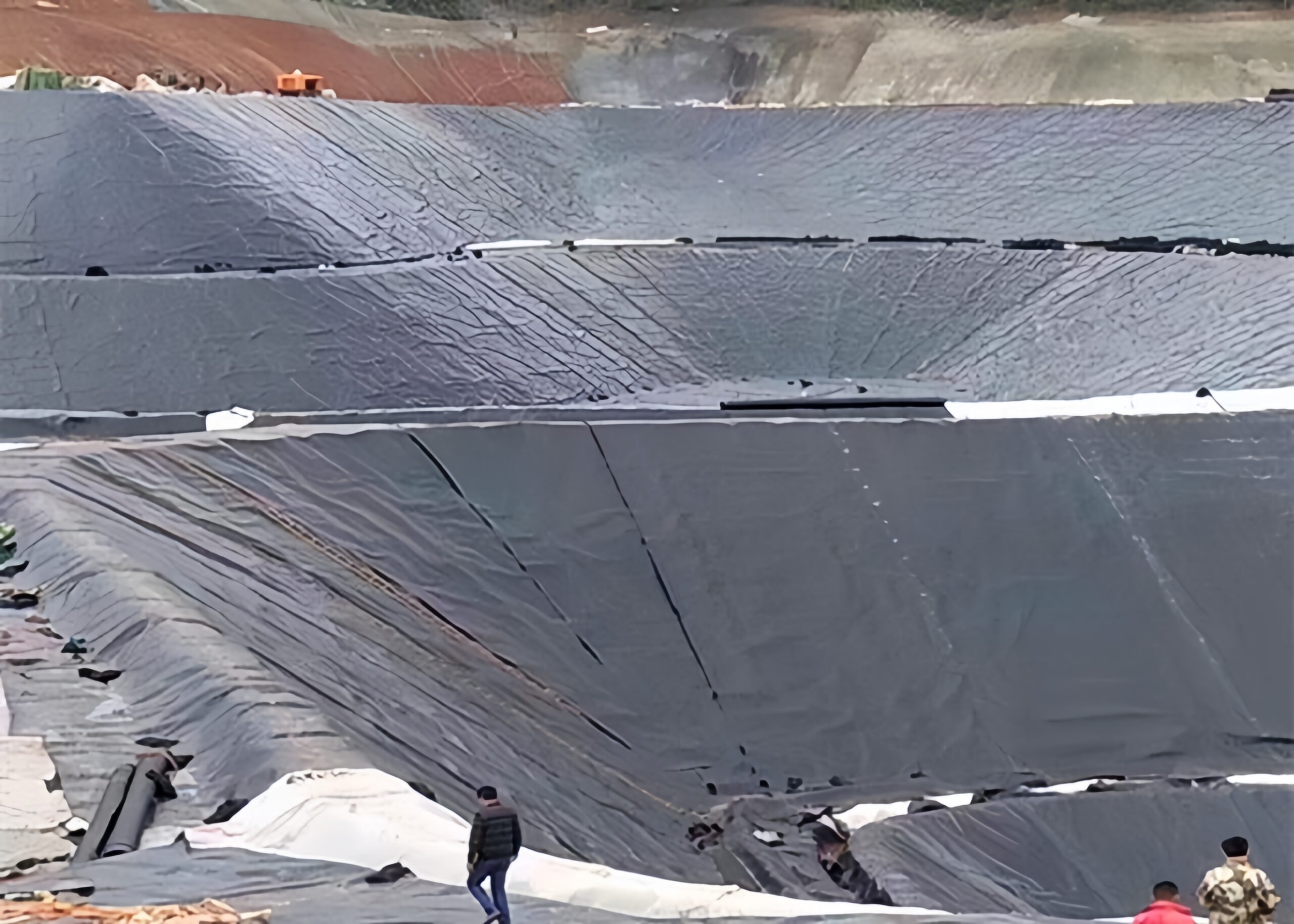 A quality assurance engineer inspecting a completed pipe boot weld on a landfill liner using a vacuum box