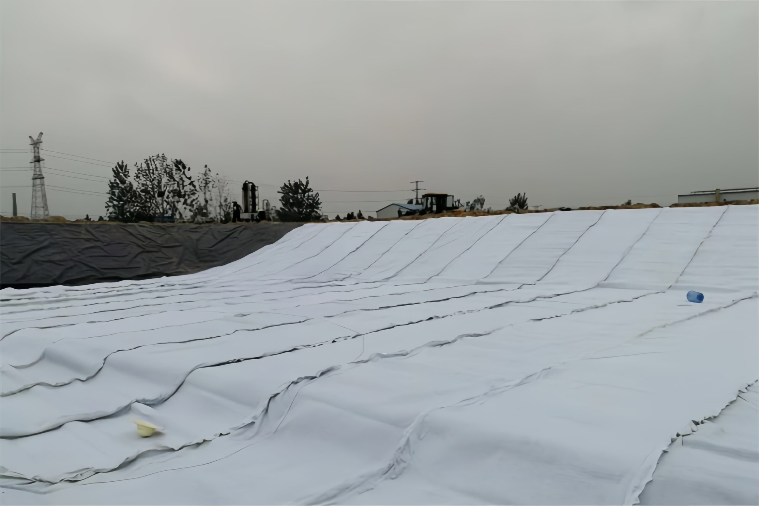 Detailed cross-section of a modern landfill liner system featuring a geocomposite drainage layer