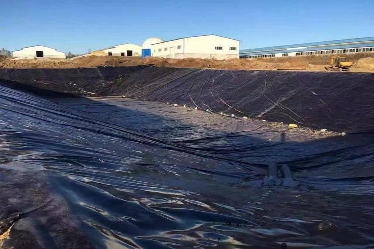 A worker inspecting a dual-track fusion weld on a black geomembrane liner seam.