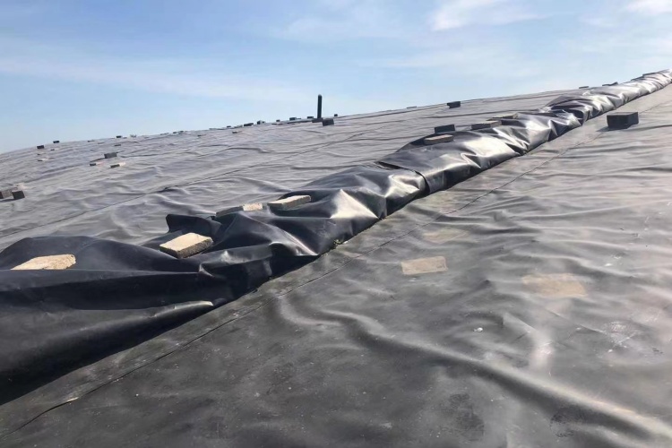 An illustration of a geomembrane being secured in an anchor trench at the top of a slope