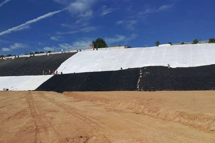 Geomembrane liner panel being secured with sandbags against the wind
