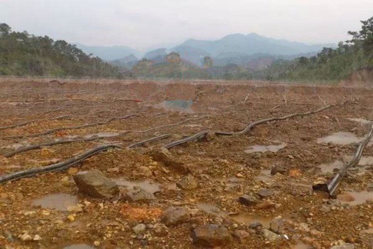 A truck placing ore on a heap leach pad, showing the scale of the operation and the liner system.