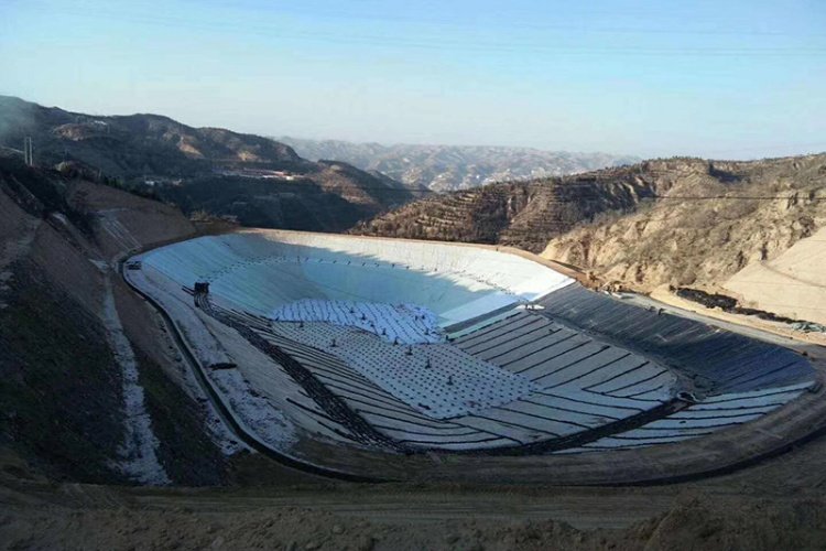 A worker welding the seams of an HDPE geomembrane for a landfill cover