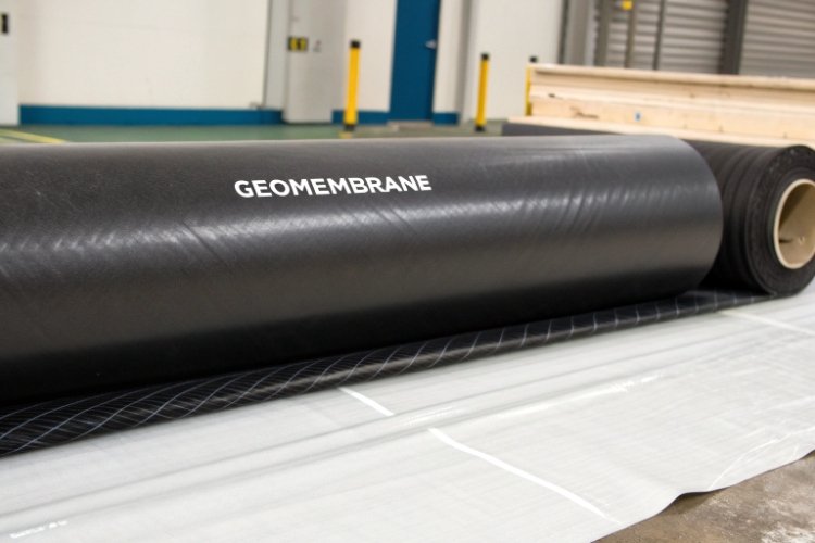 A close-up of a textured HDPE geomembrane roll with its specification label visible.