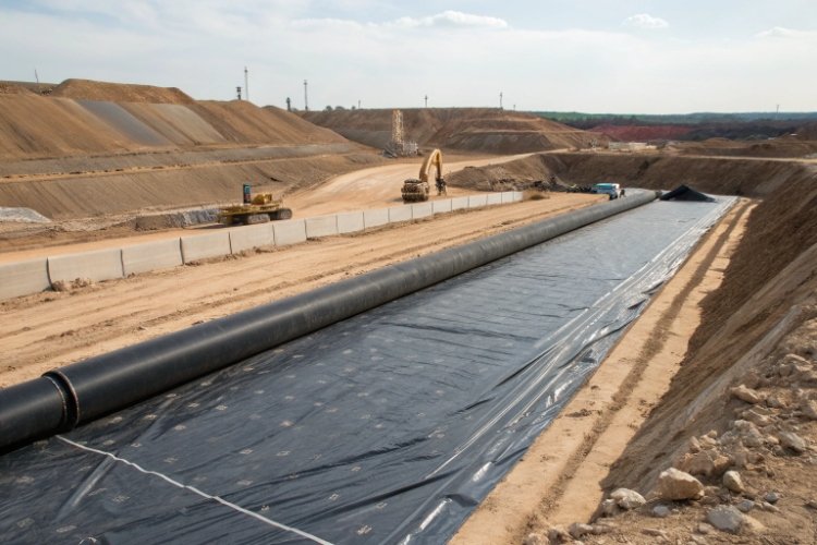 An aerial view of a massive heap leach pad with distinct sections lined with black HDPE geomembrane.