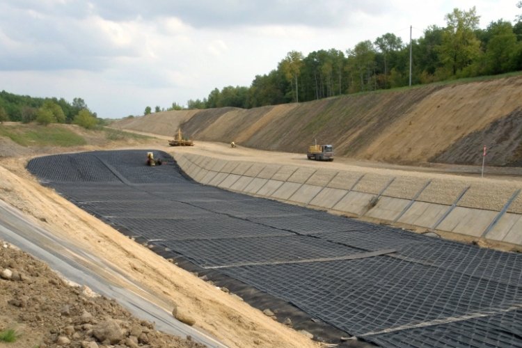 A detailed diagram showing geogrid layers reinforcing a steep landfill side slope.